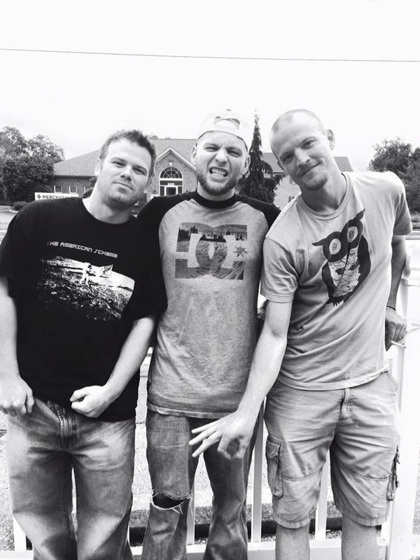 The three band members outdoors, black and white